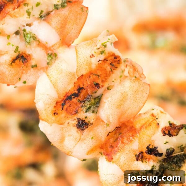 Square crop of grilled shrimp skewers with grill marks and fresh herbs.