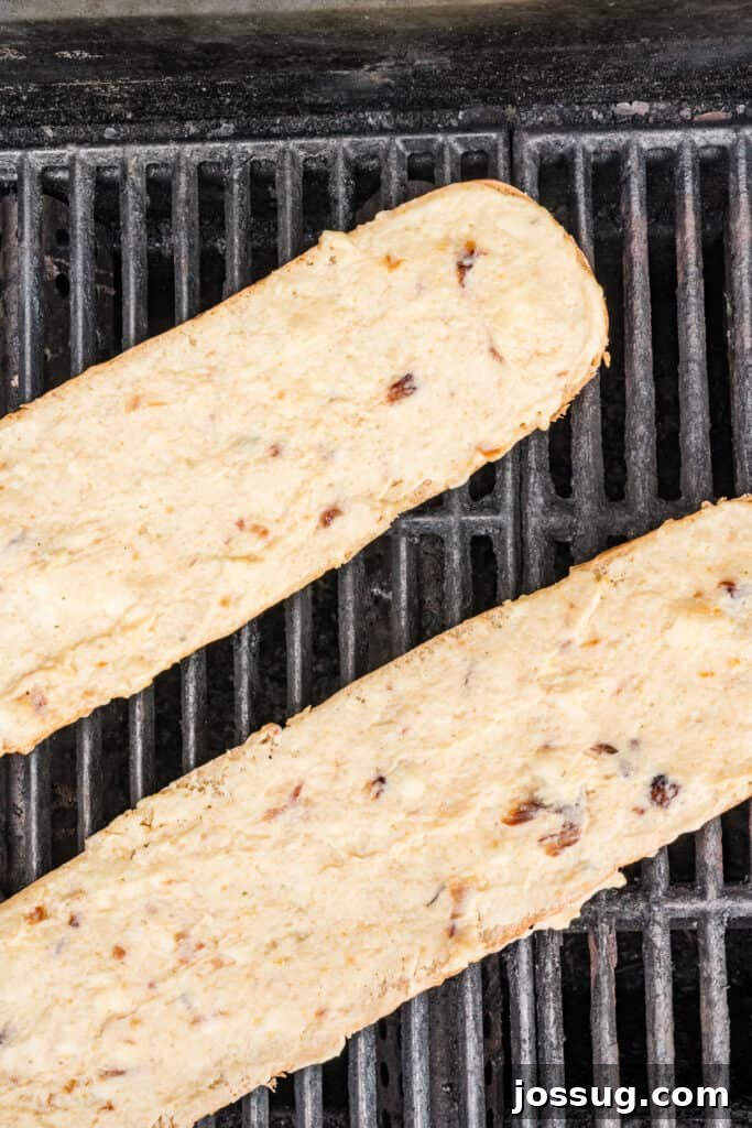 Buttered French bread placed on grill grates before cooking for Grilled Garlic Bread.