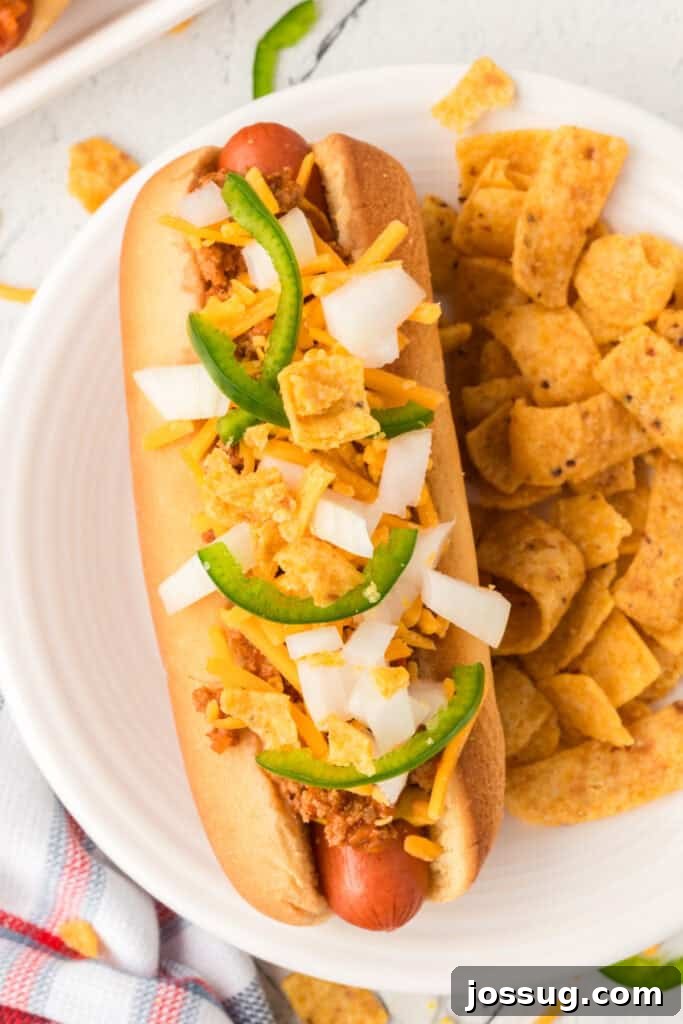 Overhead close-up of a Texas Chili Dog with chili, cheese, onions, jalapeños, and corn chips