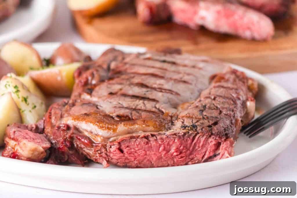 Grilled ribeye steak served with potatoes, showing the juicy pink interior and browned exterior.