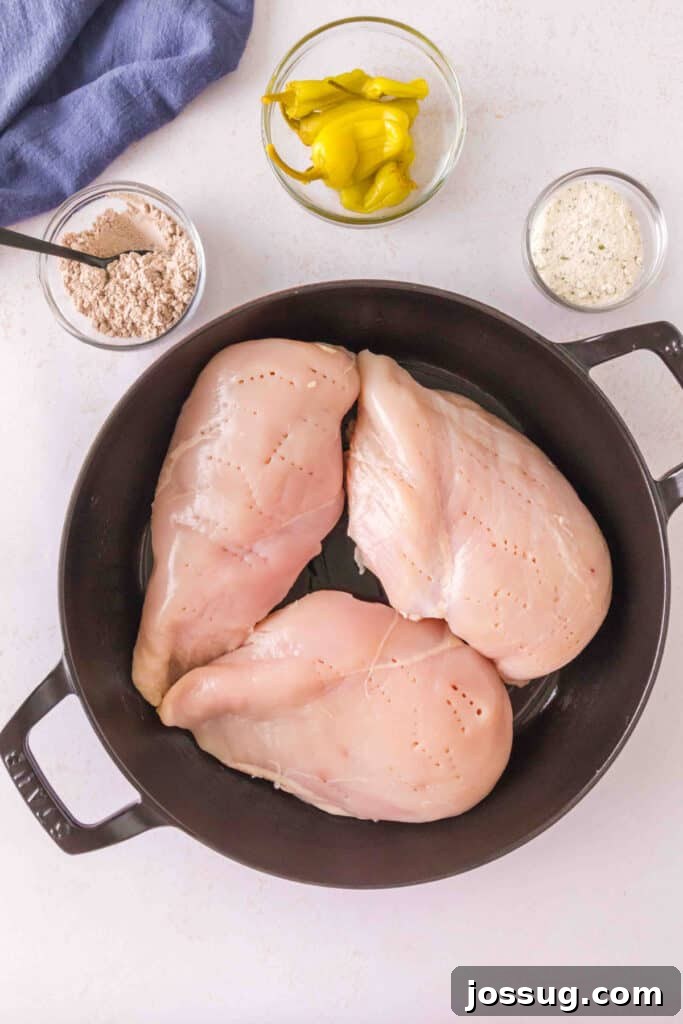 Smoked Mississippi Chicken with Ranch and Pepperoncini 5 Raw boneless chicken breasts pierced with a fork in a cast iron skillet