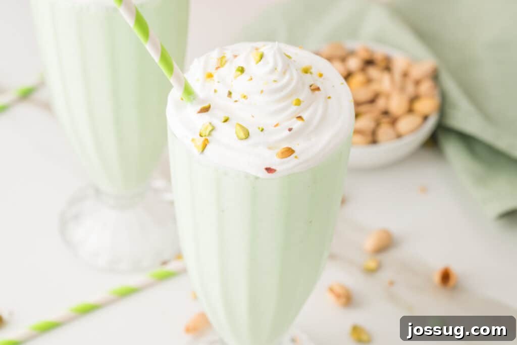 Creamy pistachio milkshake with whipped cream, chopped pistachios, and a striped straw