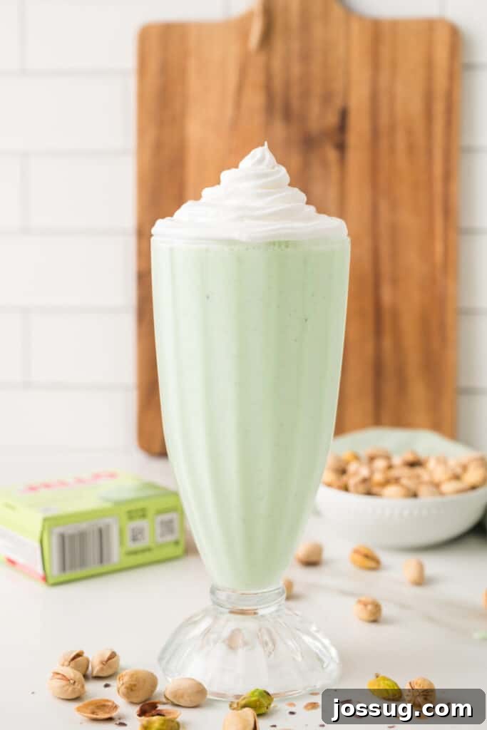 Pale green pistachio milkshake topped with a generous swirl of whipped cream