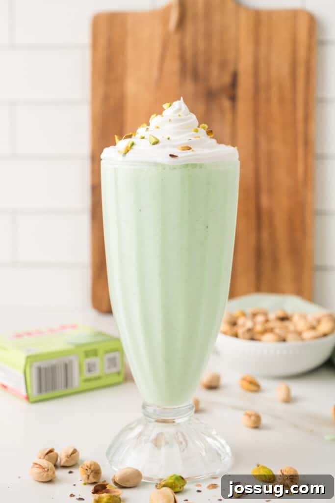 Pistachio milkshake topped with whipped cream and chopped pistachios in a tall glass