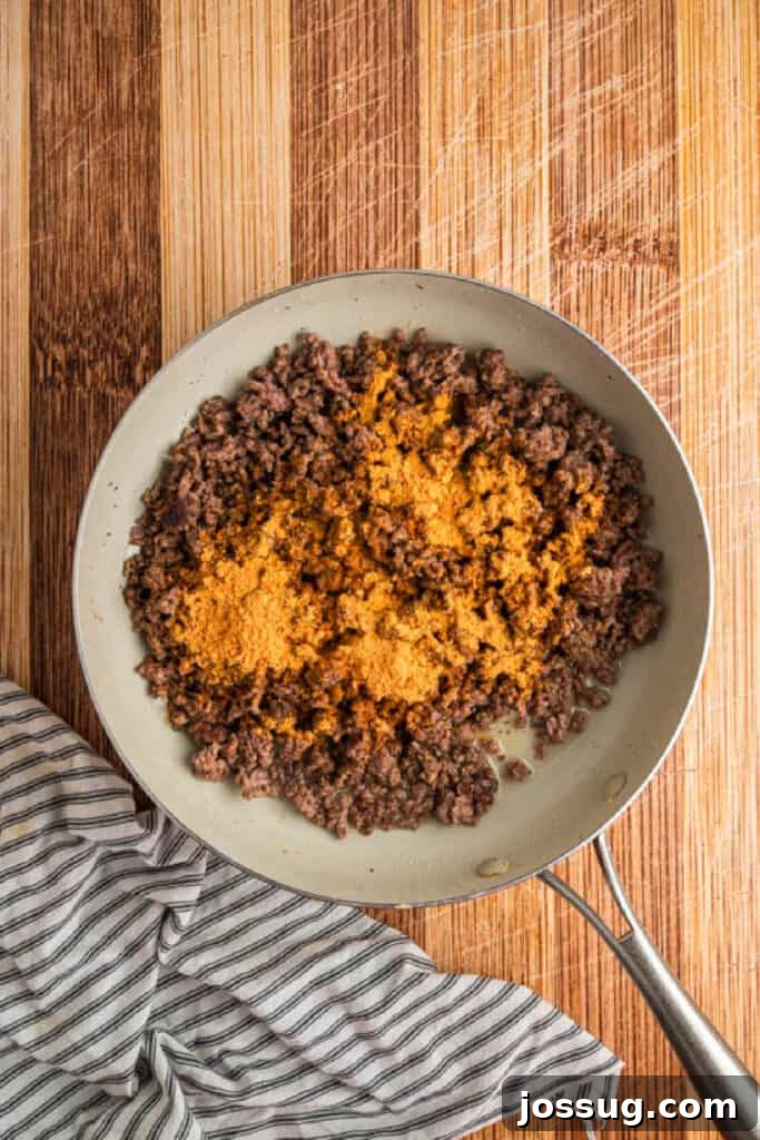 Taco seasoning added to browned ground beef in a skillet