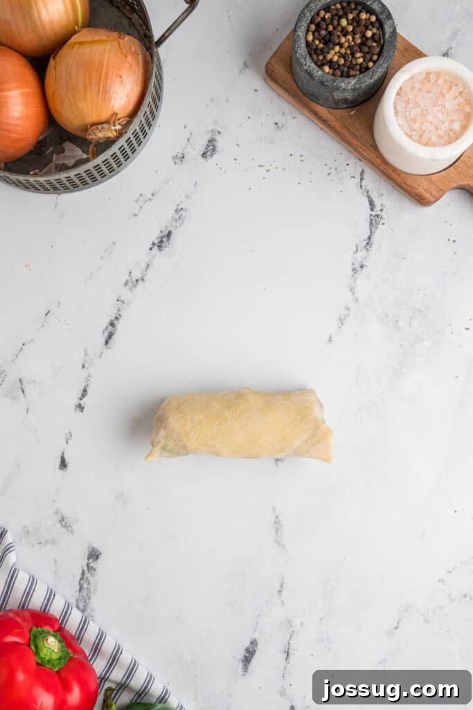 Assembled Philly Cheesesteak Egg Roll tightly rolled and ready for frying
