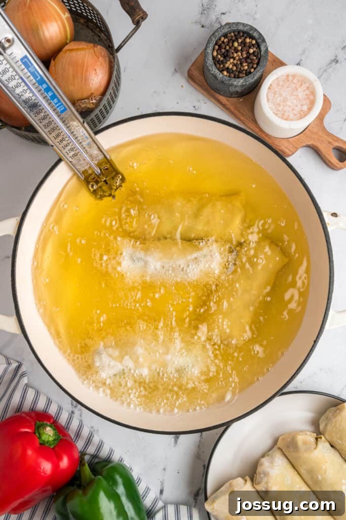 Philly Cheesesteak Egg Rolls frying in hot vegetable oil at 350°F