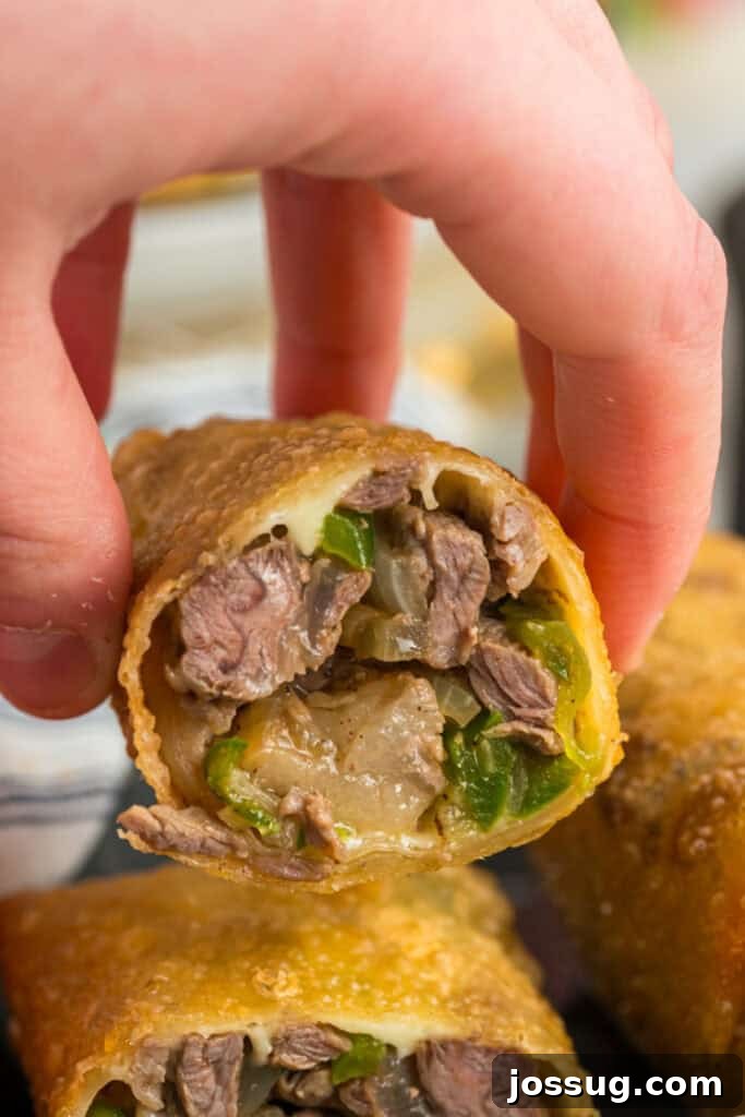 Close-up of a cut Philly Cheesesteak Egg Roll showing steak, green peppers, onions, and melted provolone