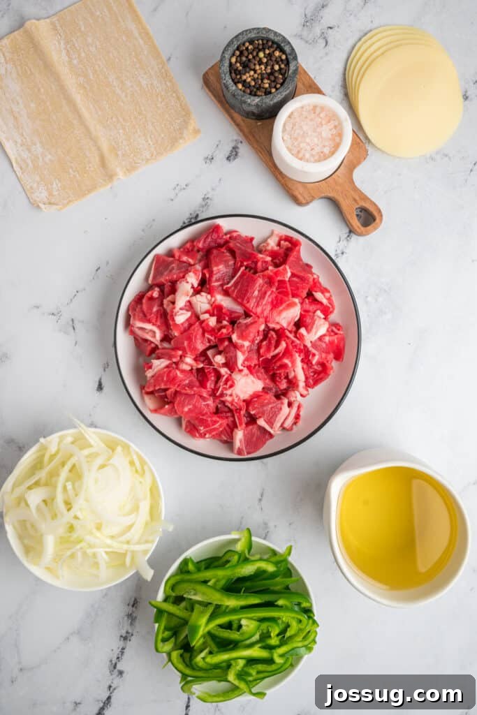 Ingredients for Philly Cheesesteak Egg Rolls including sliced steak, green bell pepper, onion, provolone, and egg roll wrappers