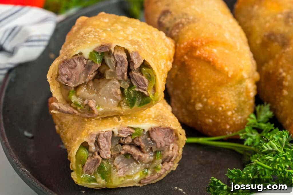Sliced Philly Cheesesteak Egg Rolls filled with steak, peppers, onions, and melted provolone on a serving plate