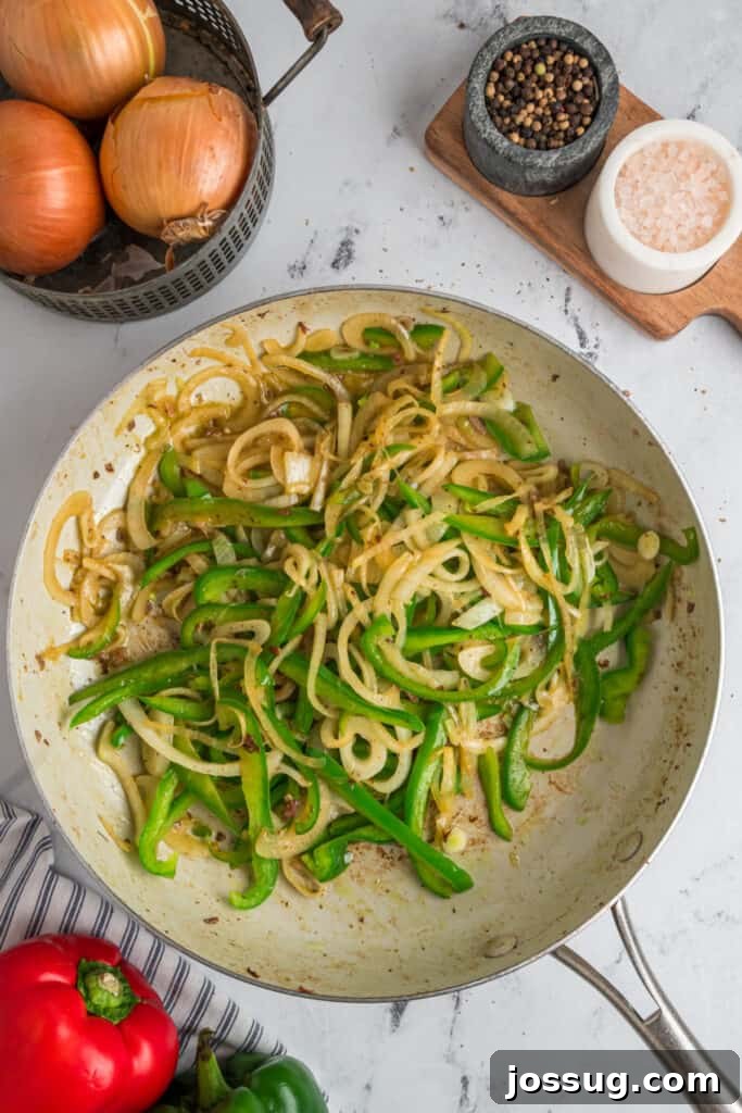 Sautéed green bell peppers and onions cooking until tender and lightly caramelized