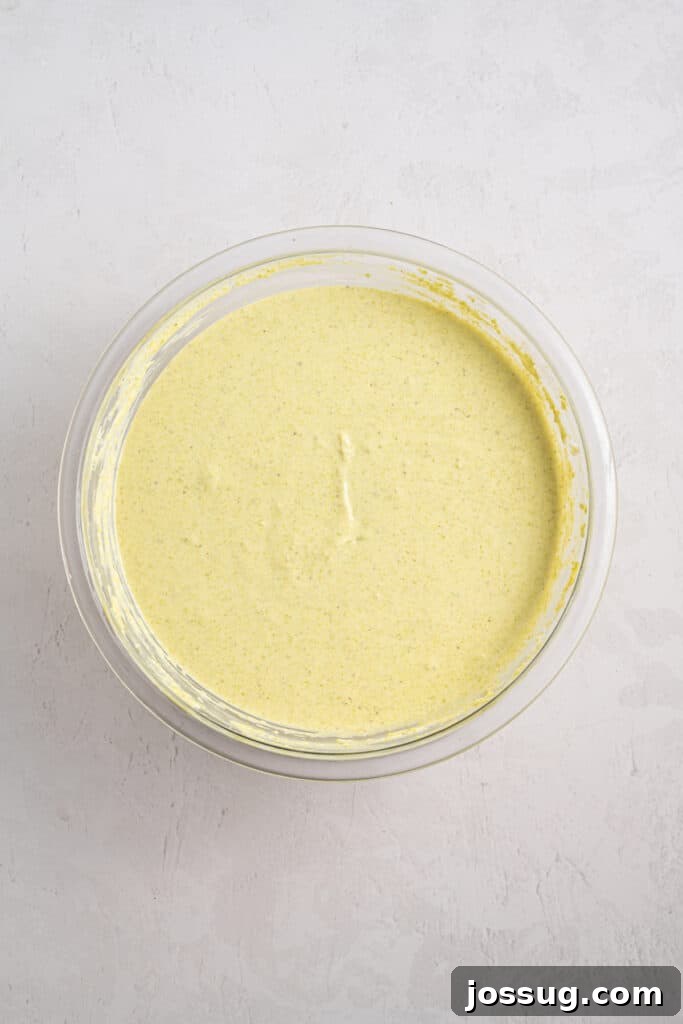 Pistachio Cheesecake with White Chocolate-Pistachio Ganache 10 Smooth pale green Pistachio Cheesecake batter in a glass mixing bowl