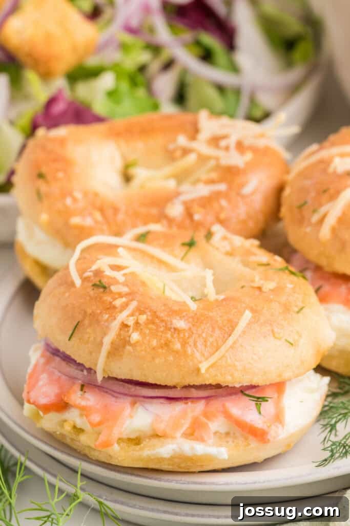 Baked Bagel and Smoked Salmon Sliders 2 Baked Bagels & Lox Slider served on a plate with smoked salmon, cream cheese, red onion, and dill