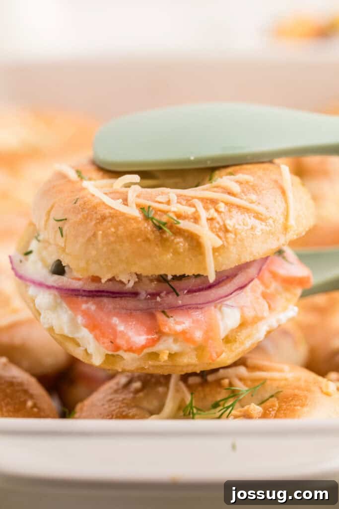 Baked Bagel and Smoked Salmon Sliders 19 Baked Bagels & Lox Slider lifted from the pan showing smoked salmon, cream cheese, red onion, capers, and dill