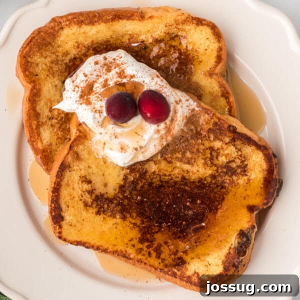 Baked Bagel and Smoked Salmon Sliders 25 Eggnog French Toast topped with whipped cream, cinnamon, maple syrup, and cranberries on a white plate.