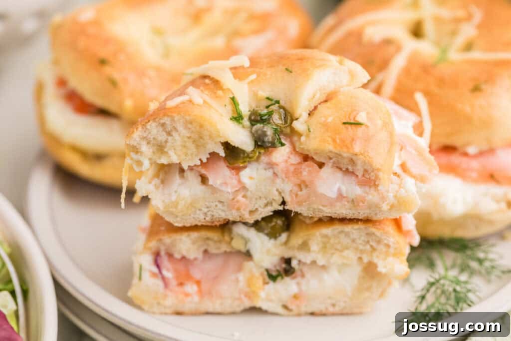 Baked Bagel and Smoked Salmon Sliders 4 Halved Baked Bagels & Lox Sliders stacked on a plate showing the smoked salmon and cream cheese filling