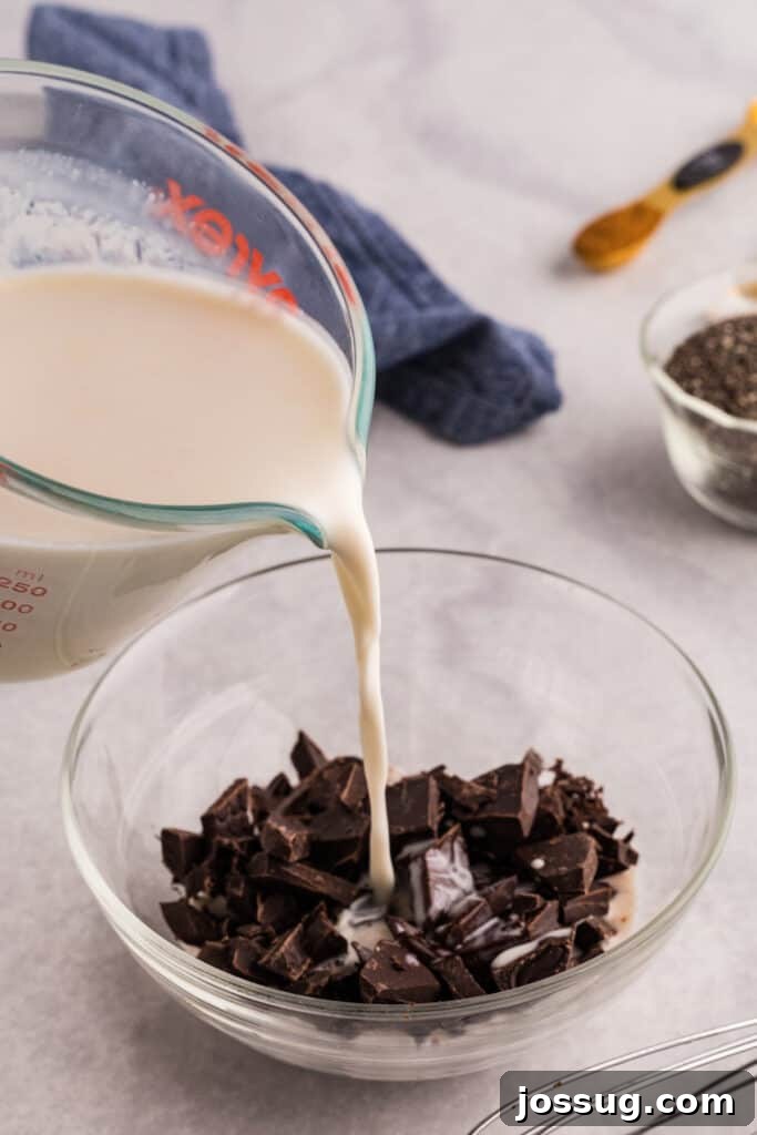 Creamy Chocolate Chia Pudding Recipe 5 Warm cream mixture being poured over chopped dark chocolate in a glass bowl