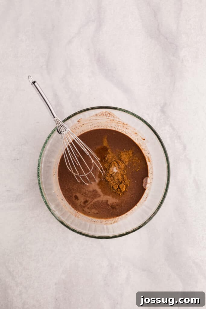 Creamy Chocolate Chia Pudding Recipe 6 Cinnamon added to melted chocolate mixture in a glass bowl with a whisk