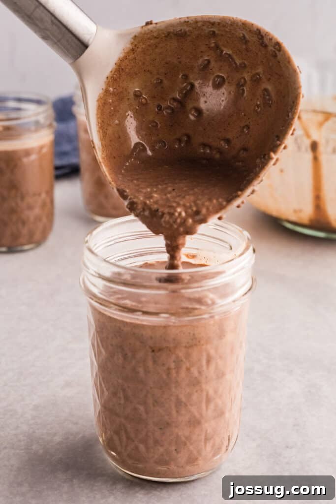 Creamy Chocolate Chia Pudding Recipe 9 Chocolate chia pudding mixture being spooned into individual glass jars