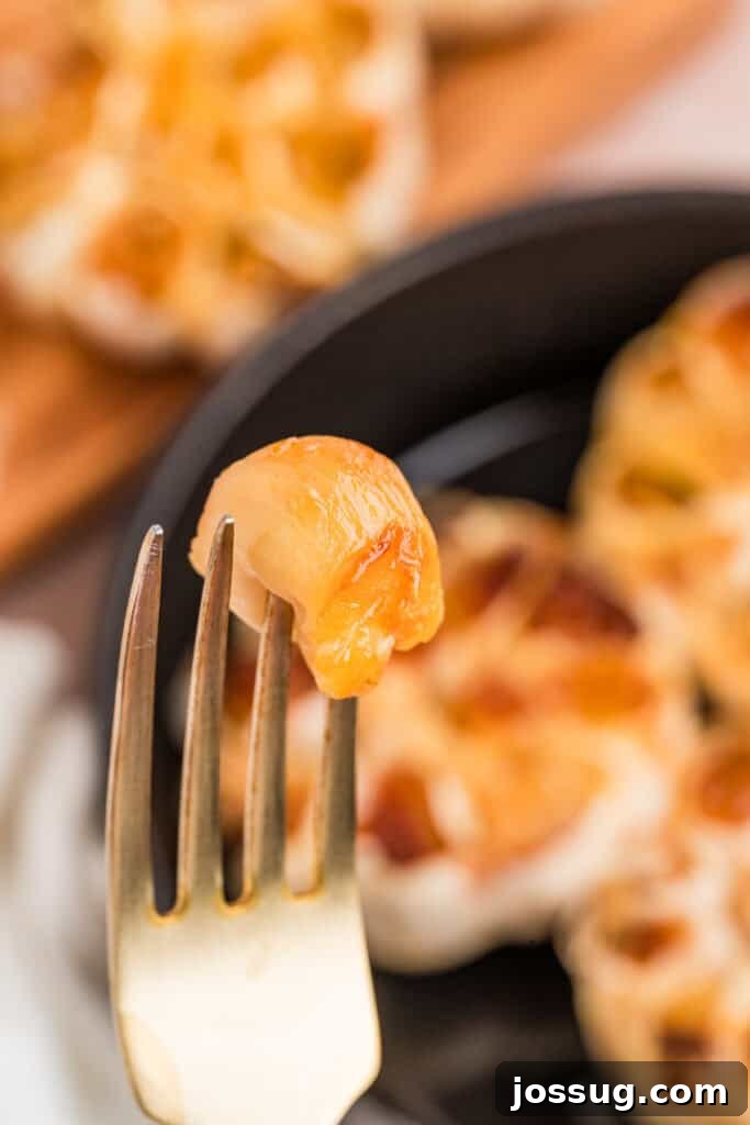 Soft caramelized roasted garlic clove held on a fork