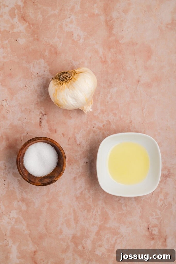 Ingredients for roasted garlic including a whole garlic bulb, olive oil, and salt