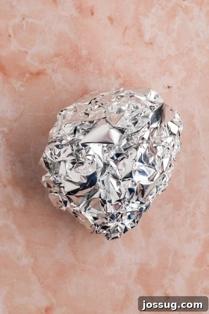 Prepared garlic bulb wrapped tightly in aluminum foil before cooking