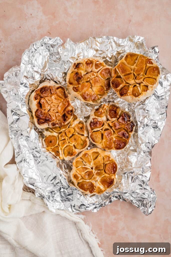 Several bulbs of roasted garlic unwrapped from foil after grilling